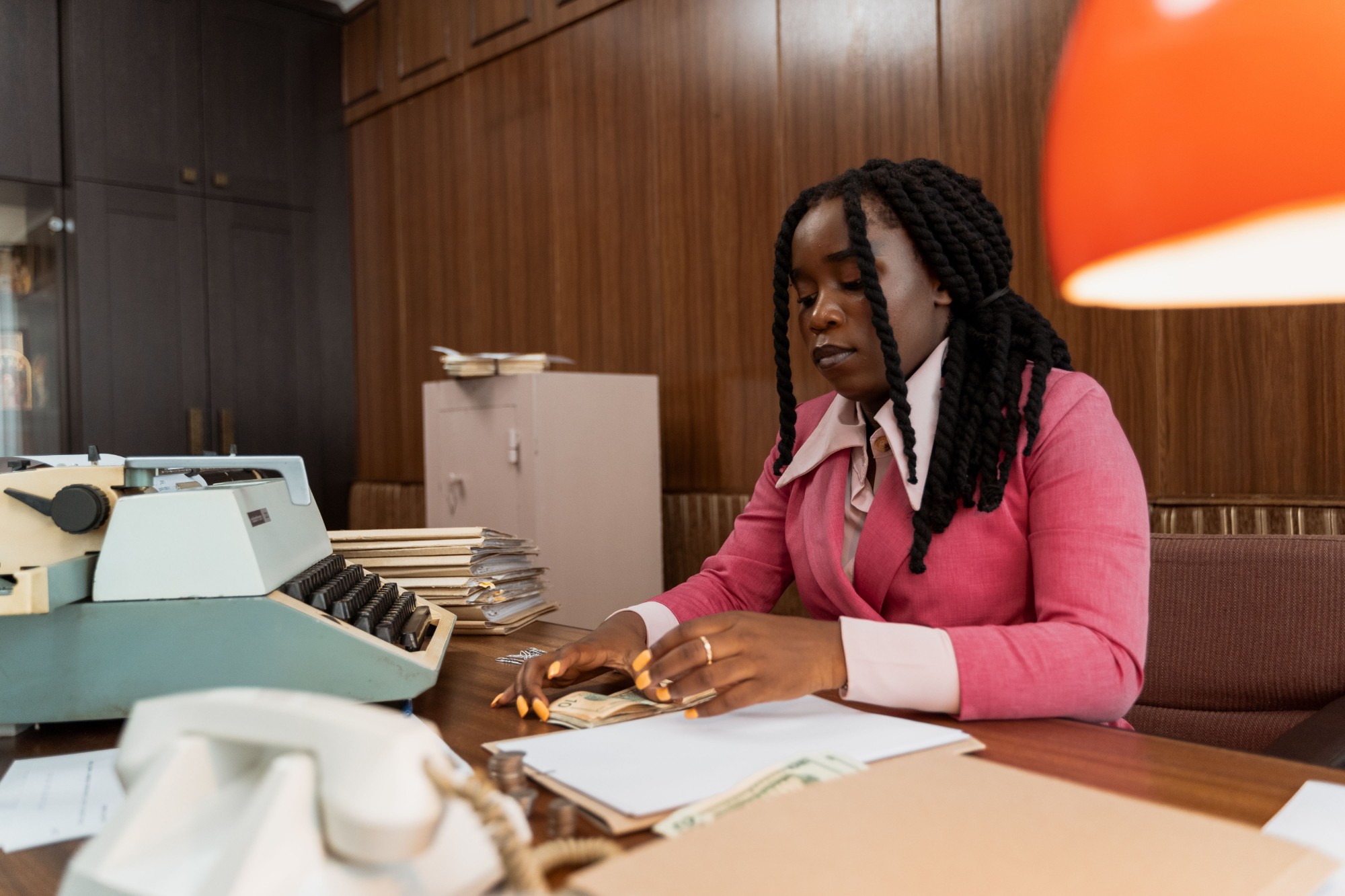 Business owner counting cash at a desk while reviewing paperwork